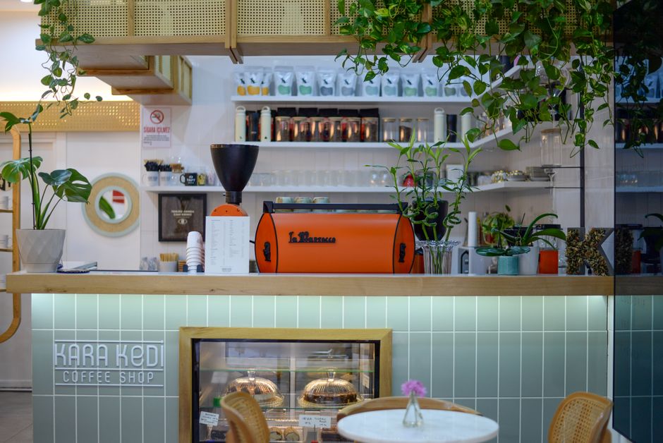 Stylish and modern coffee shop interior featuring plants and a vibrant coffee machine.