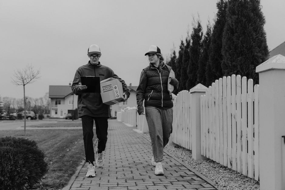 Two couriers delivering packages in a residential neighborhood.